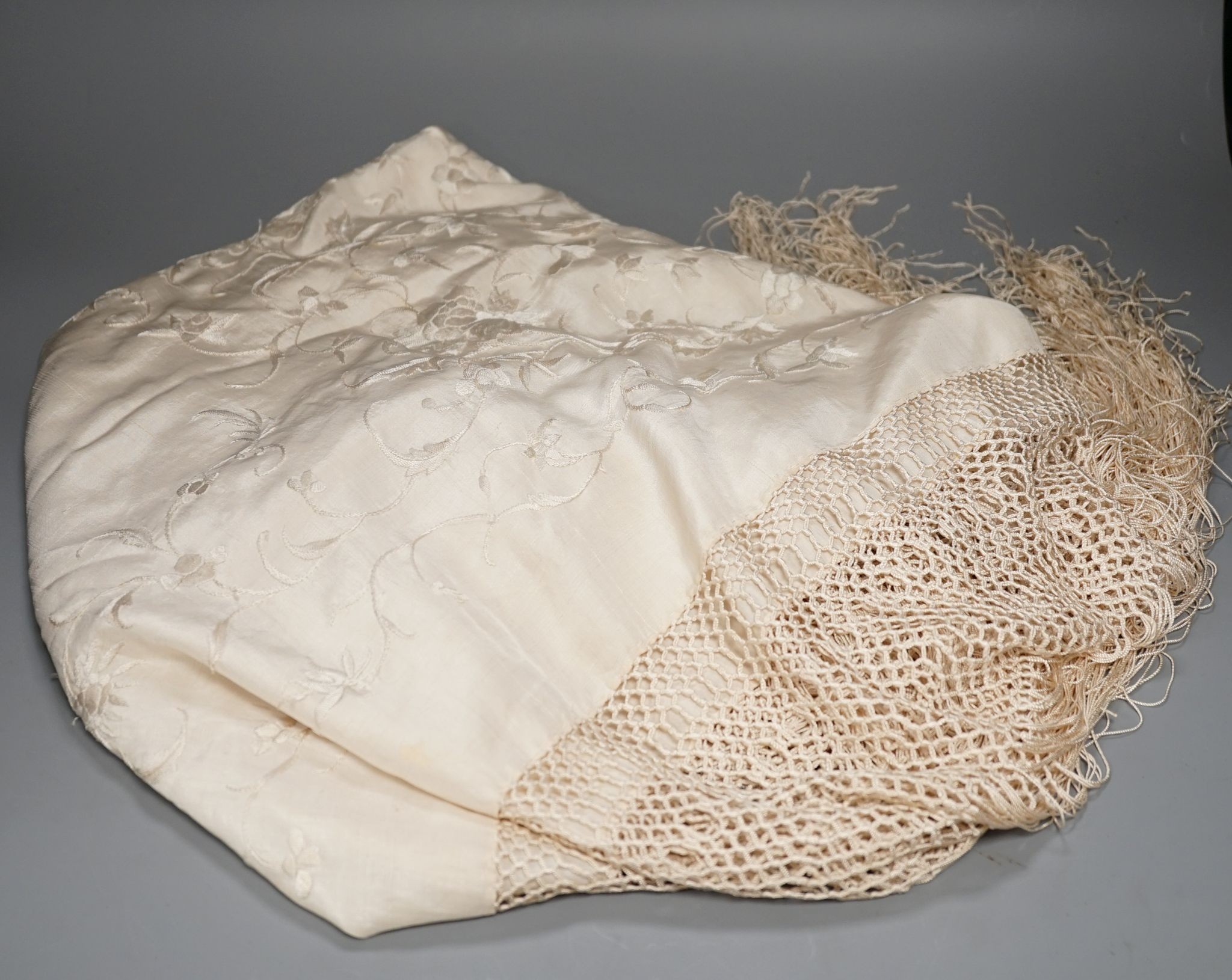 A Chinese cream on cream silk, embroidered shawl with a tasselled fringed edge, 160 cms wide x 160 square.